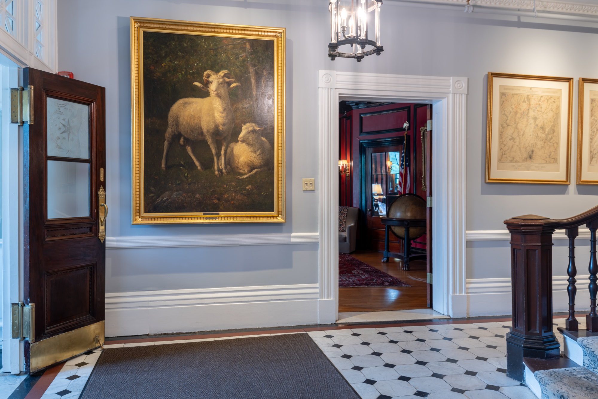 Entrance foyer displaying large gold-framed paintings and tiled floor.