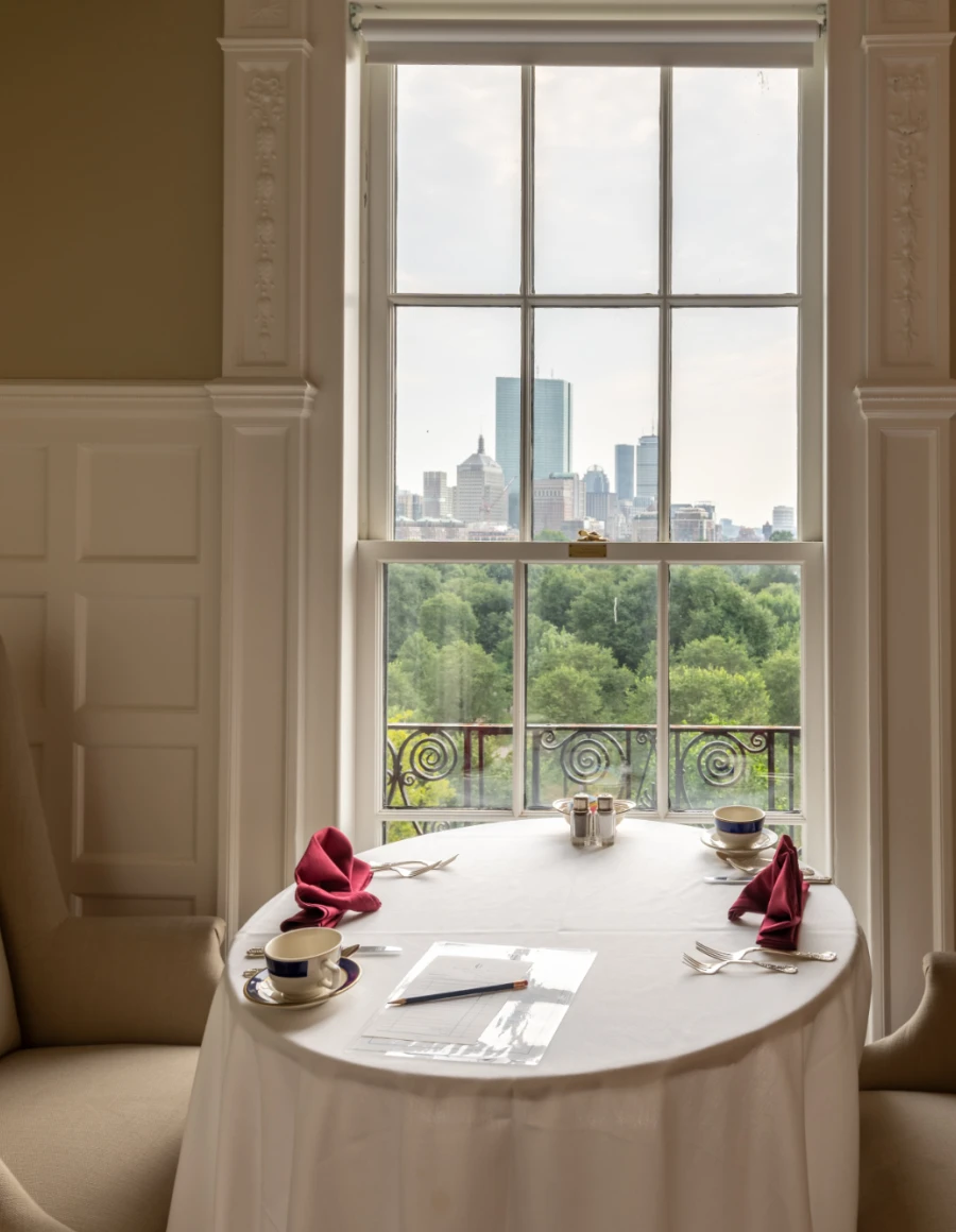 Sophisticated dining table and chairs, set against large window.